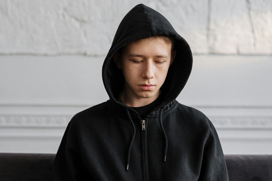 Young man in hoodie sitting on sofa. Photo by cottonbro studio via Pexels